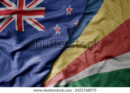 big waving national colorful flag of seychelles and national flag of new zealand . macro