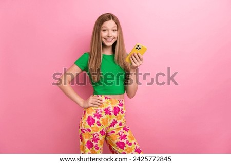 Photo portrait of charming teen girl hold gadget read comment dressed stylish green clothes isolated on pink color background