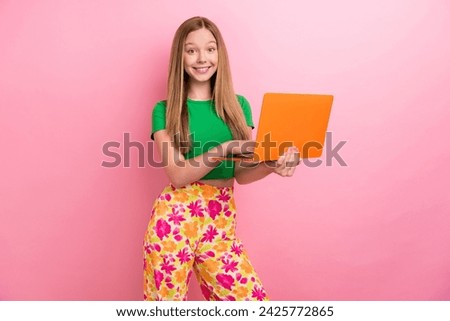 Photo portrait of charming teen girl hold orange netbook dressed stylish green clothes isolated on pink color background