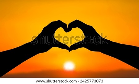 Silhouette of hands making a heart in front of the sunset