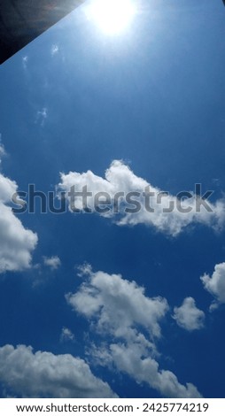 Panorama of blue and cloudy sky, hot sun overhead around 12 noon on a sunny day