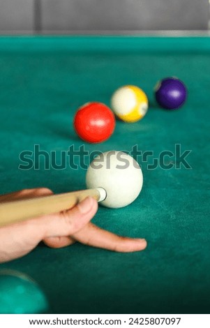 Hand with cue aiming on billiard ball at table. Selective focus
