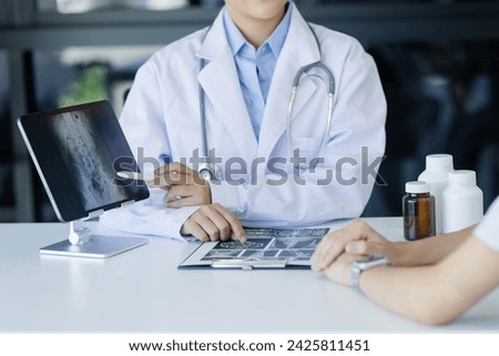 Asian female doctor explain to patient and looking at xrays indoors office, healthcare and medical concept.