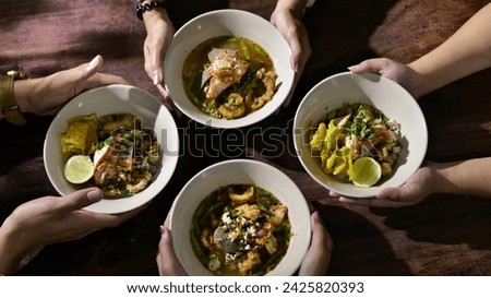 4 pairs of hand holding noodle bowls. It's the Thai style noodle that hot and spicy. Royalty-Free Stock Photo #2425820393