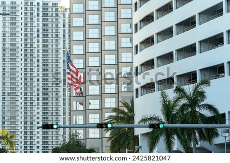 USA national flag waving on wind in front of Miami urban skyline. American stars and stripes spangled banner as symbol of democracy