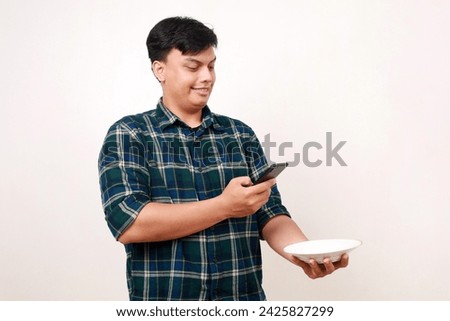 Happy young asian man photographing his food on the plate