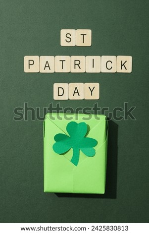 Green box with clover leaf and wooden letters on green background, top view