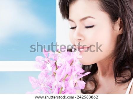 Close up of a young healthy woman smelling flowers.