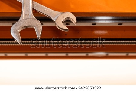 wrenches on a CNC machine are orange, the shaft and guide rails of the machine are visible
 Royalty-Free Stock Photo #2425853329