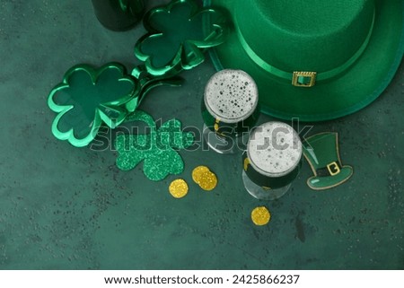 Glasses of green beer with clover leaves and Leprechaun's hat on green background. St. Patrick's Day celebration.