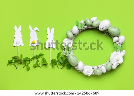 Easter wreath with flowers, eggs and butterflies on light green background