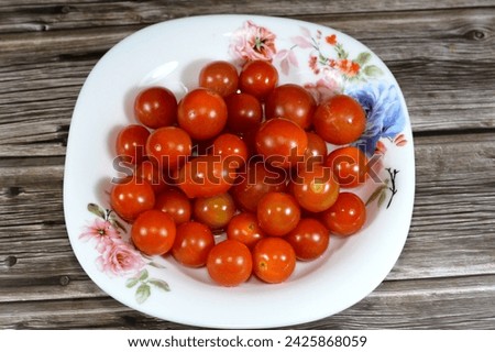 The cherry tomato, a type of small round tomato believed to be an intermediate genetic admixture between wild currant-type tomatoes and domesticated garden tomatoes, Cherry tomatoes range in size Royalty-Free Stock Photo #2425868059