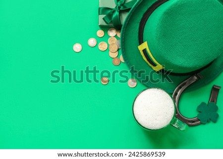 Glass of beer with horseshoe, coins, gift box and leprechaun hat on green background. St. Patrick's Day celebration