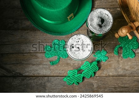 Glasses of beer with clover and leprechaun hat on wooden table. St. Patrick's Day celebration
