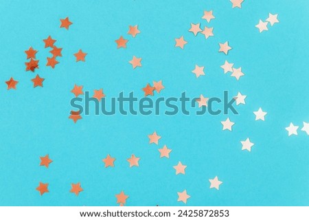Golden confetti on blue background. Birthday party, holiday concept. Top view, copy space.