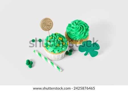 Tasty cupcakes with decor for St. Patrick's Day on white background
