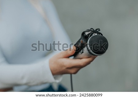 Journalist in white dress holding microphone and sound recorder dictaphone at NEWS conference