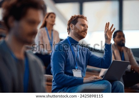 Male entrepreneur raising his hand to ask a question while attending business seminar in conference room.  Royalty-Free Stock Photo #2425898115