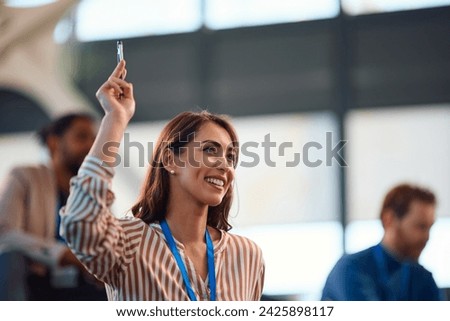 Happy female entrepreneur asking a question from the audience during a  business conference in convention center. Copy space.  Royalty-Free Stock Photo #2425898117