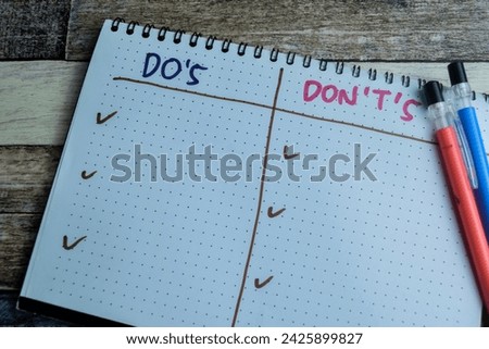Concept of Do's and Don't's write on book. Supported by an additional services isolated on Wooden Table.