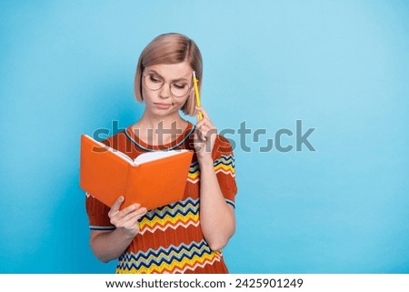 Photo of pensive minded woman dressed knit t-shirt in eyewear planing week look at copybook pen on head isolated on blue color background