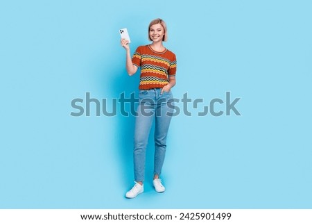 Full size photo of satisfied good mood girl wear striped t-shirt jeans demonstrate smartphone on sale isolated on blue color background