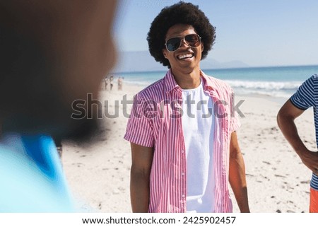 Young African American men enjoy a sunny beach day. Casual attire suggests a relaxed outdoor gathering among friends. Royalty-Free Stock Photo #2425902457