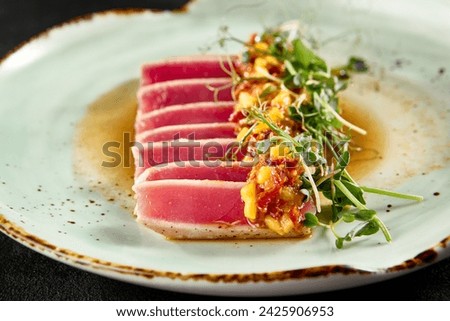Seared tuna tataki with mango salsa and ponzu sauce on a speckled ceramic plate. Royalty-Free Stock Photo #2425906953