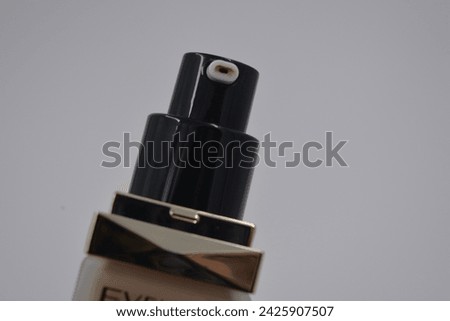 Women's cosmetics, accessories and things, foundation for moisturizing, care, facial skin care in a beautiful glass bottle with a matte black cap placed on a white plastic background.