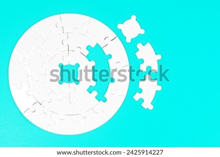 Top view of an incomplete white circular jigsaw puzzle with three final elements on a light blue background. Royalty-Free Stock Photo #2425914227