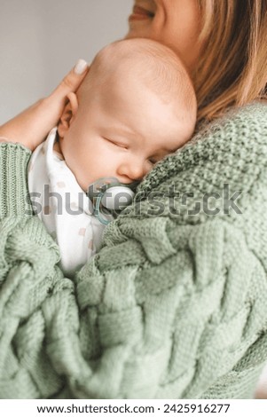 Woman holding baby boy sleeping on mother hands close up. Motherhood. 