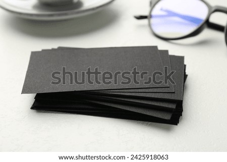 Blank black business cards on white table, closeup. Mockup for design