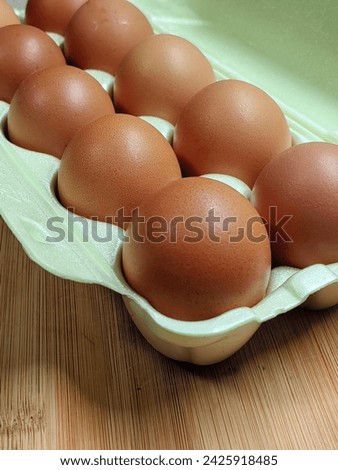 Brown chicken eggs as a background image. Top view of beige chicken eggs in an open green plastic egg container. Brown chicken eggs in a green plastic container.
