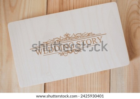 Wooden photo box for photo storage on wooden background. Box with flash with laser engraving "wedding story" set for the photographer, presentable set of photos, luxury feedback to client. Royalty-Free Stock Photo #2425930401