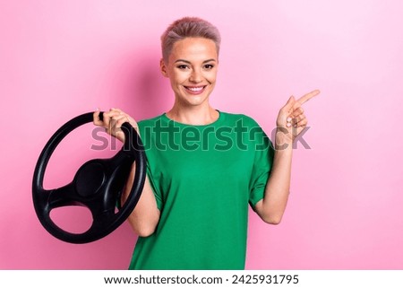 Photo of pretty cheerful girl hold wheel direct finger empty space information isolated on pink color background