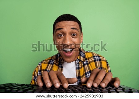 Photo of handsome astonished man open mouth unbelievable fingers write keyboard isolated on green color background