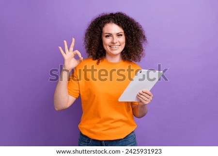 Photo of cool funky woman wear orange t-shirt showing okey sign texting modern device isolated purple color background