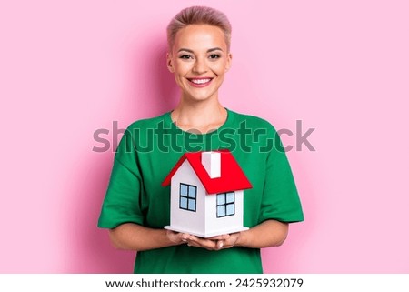 Photo of cheerful nice girl toothy smile arms hold showing small house isolated on pink color background