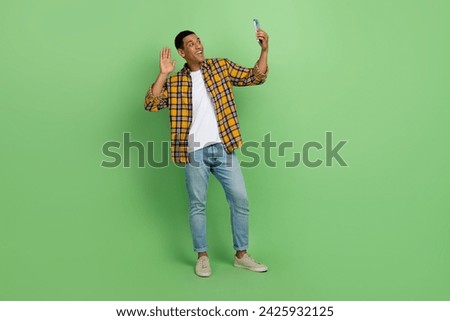 Full size portrait of positive person hold smart phone take selfie arm waving hi empty space isolated on green color background