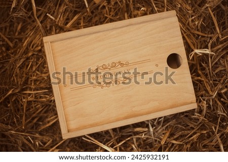 Wooden photo box for photo storage on straw background. Box with flash with laser engraving "wedding day" set for the photographer, presentable set of photos, luxury feedback to client. Royalty-Free Stock Photo #2425932191