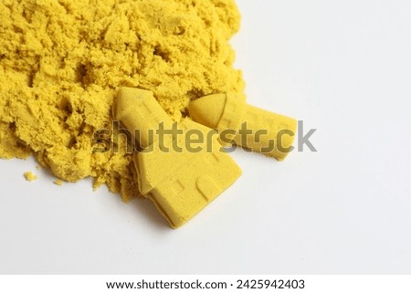 Castle and tower made of yellow kinetic sand on white background, top view