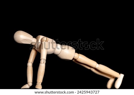 Wooden figure doing push-ups in front of a black background