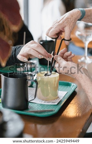 Two women cutting a candle wick together Royalty-Free Stock Photo #2425949449