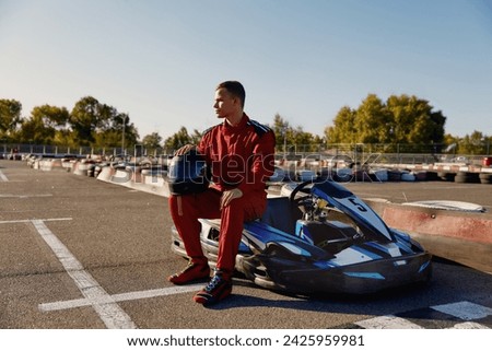 Handsome man driver sitting at his go-kart car waiting for start of competition Royalty-Free Stock Photo #2425959981