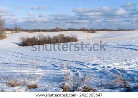 An agriculture field with oil pump jack in winter  season next to growing city behing the horizon line