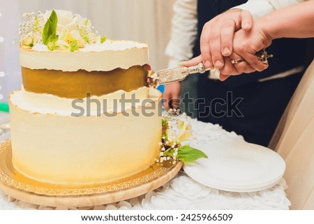 Three-tiered white wedding cake decorated with flowers from mastic on a white wooden table. Picture for a menu or a confectionery catalog with copy space