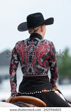 western horse show attire female horse rider wearing bright shirt with bling and western fashion pattern western pleasure horse show apparel for horse show competition in  western riding vertical  Royalty-Free Stock Photo #2425966825