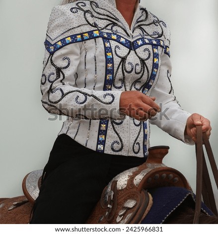 western horse show attire female horse rider wearing bright shirt with bling and western fashion pattern western pleasure horse show apparel for horse show competition in  western riding vertical  Royalty-Free Stock Photo #2425966831