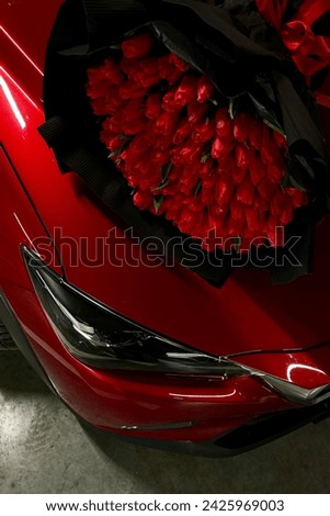 A large bouquet of bright red tulips on a red car