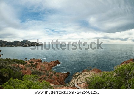Mediterranean shoreline - The Mediterranean Sea seen from the Dramont cliffs. The red rocks of the Estérel plunge into the blue of the sea. Royalty-Free Stock Photo #2425981255